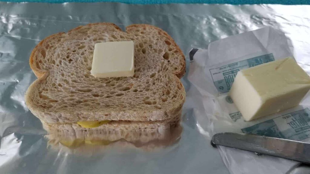 Two slices of sourdough bread with a pat of butter, on a backdrop of foil