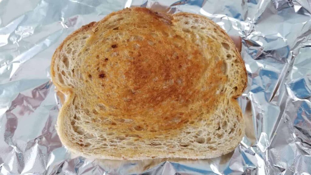Toasted piece of sourdough bread on a foil background