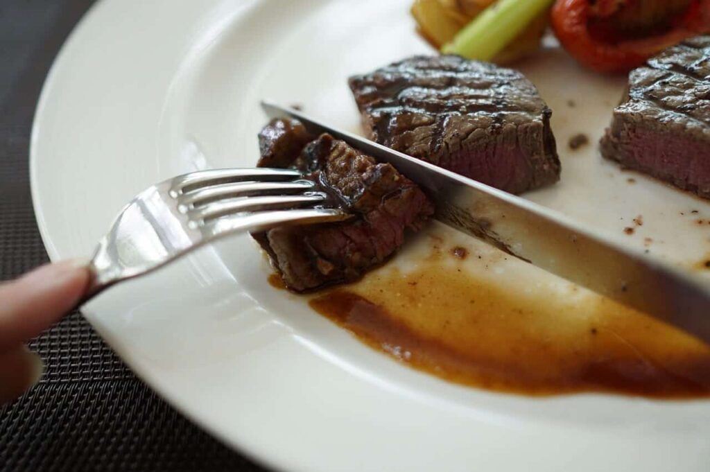 Piece of steak being cut into a bite size morsels