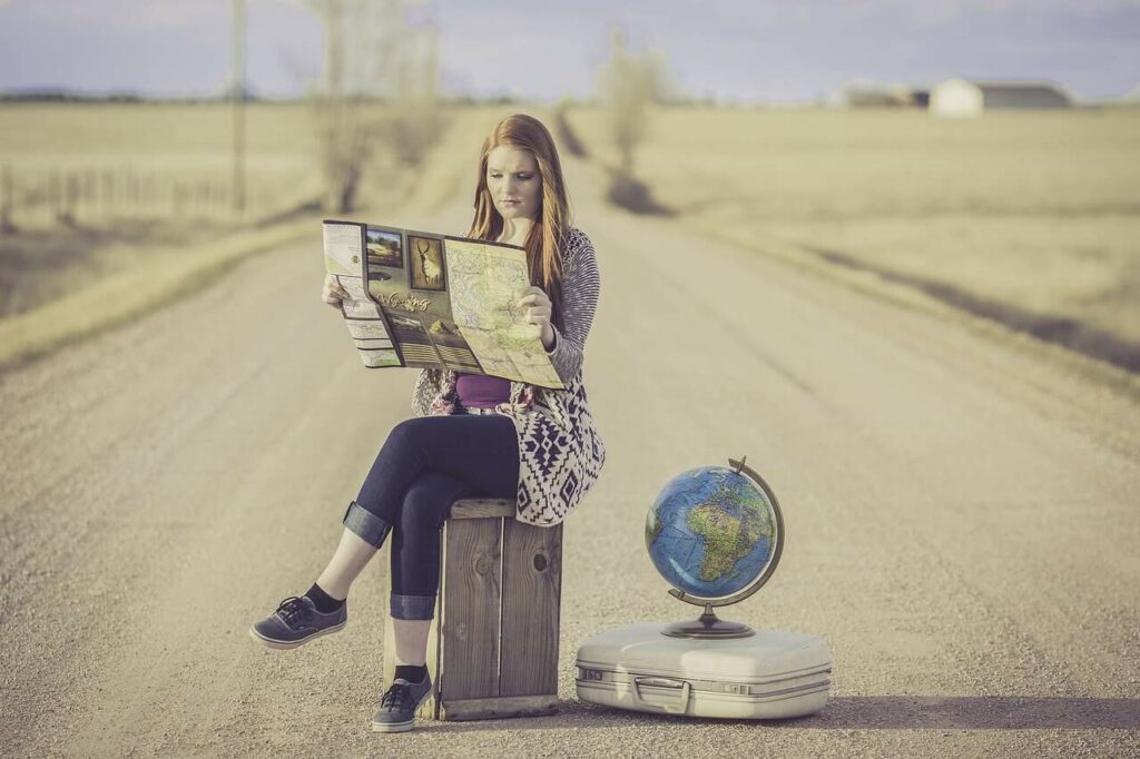 Woman sitting on the tarmac with a map in her hand and a globe in the background