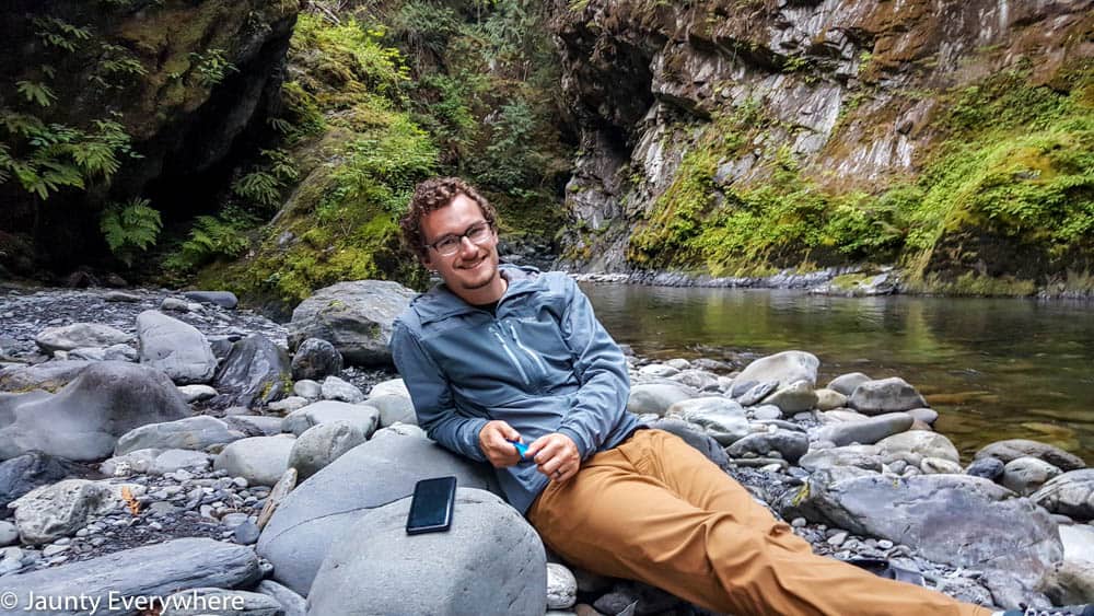 hiker resting on a rocky river bank