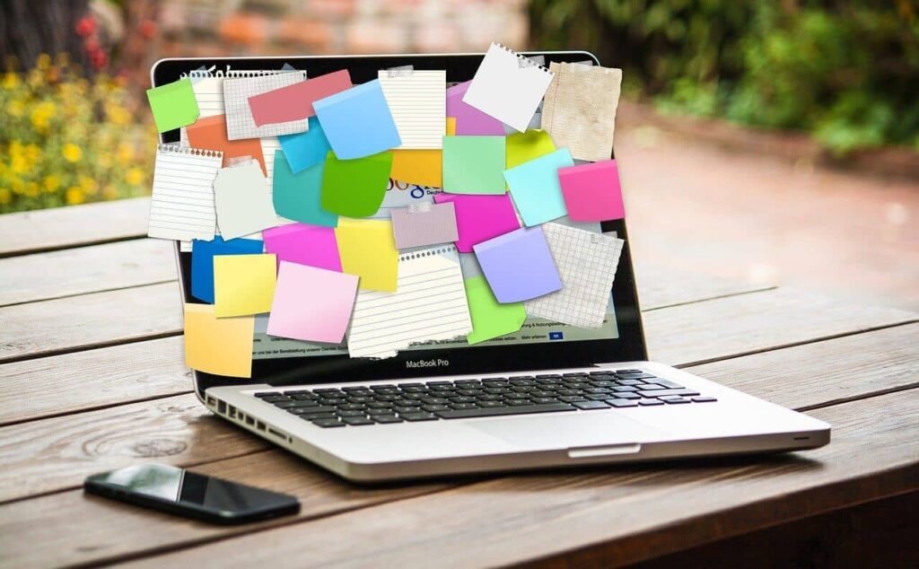 laptop covered in post-it notes and scraps of paper