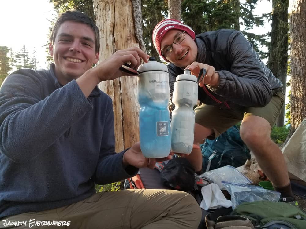 Jordan Stanton and Andrew Bywater's smiling and comparing water bottles. Backpacking tips for beginners.