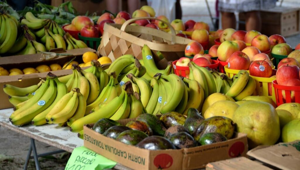 bananas, apples, avocados and grapefruit piled high at an outdoor market