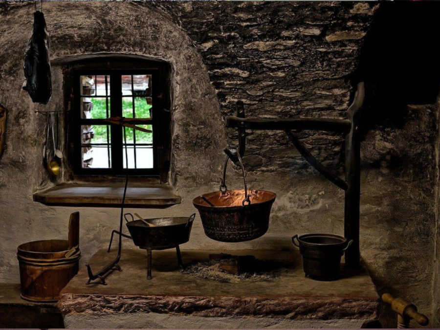 historic stone house with copper cookware over an open fire