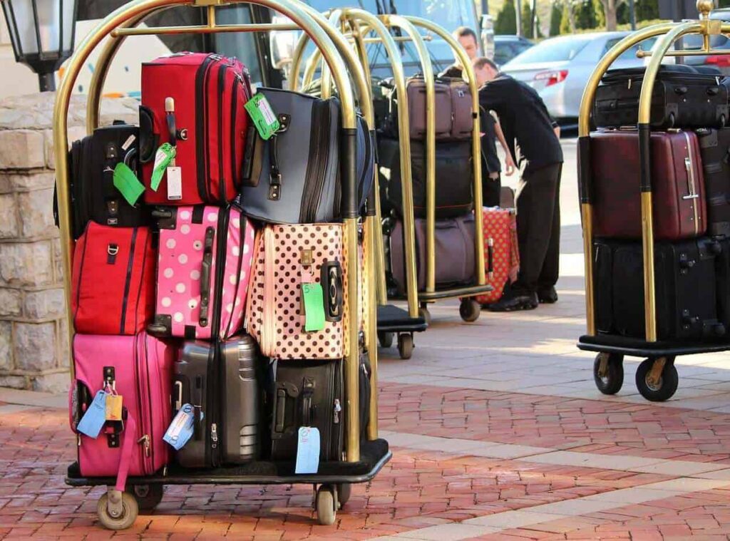 Enneagram and travel type three is most likely to take Stacks of suitcases on hotel carts at check in. Two valets work in the background.