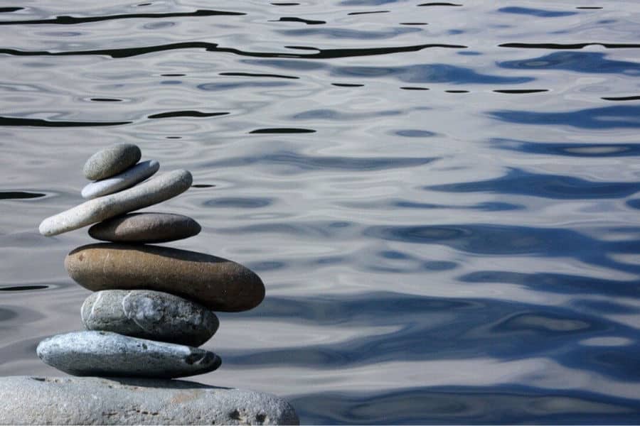 A pile of rocks next to a smooth body of water, staycations are stress free