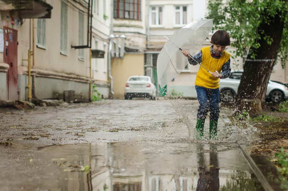 little boy wearing a bright yellow shirt, playing in the puddles