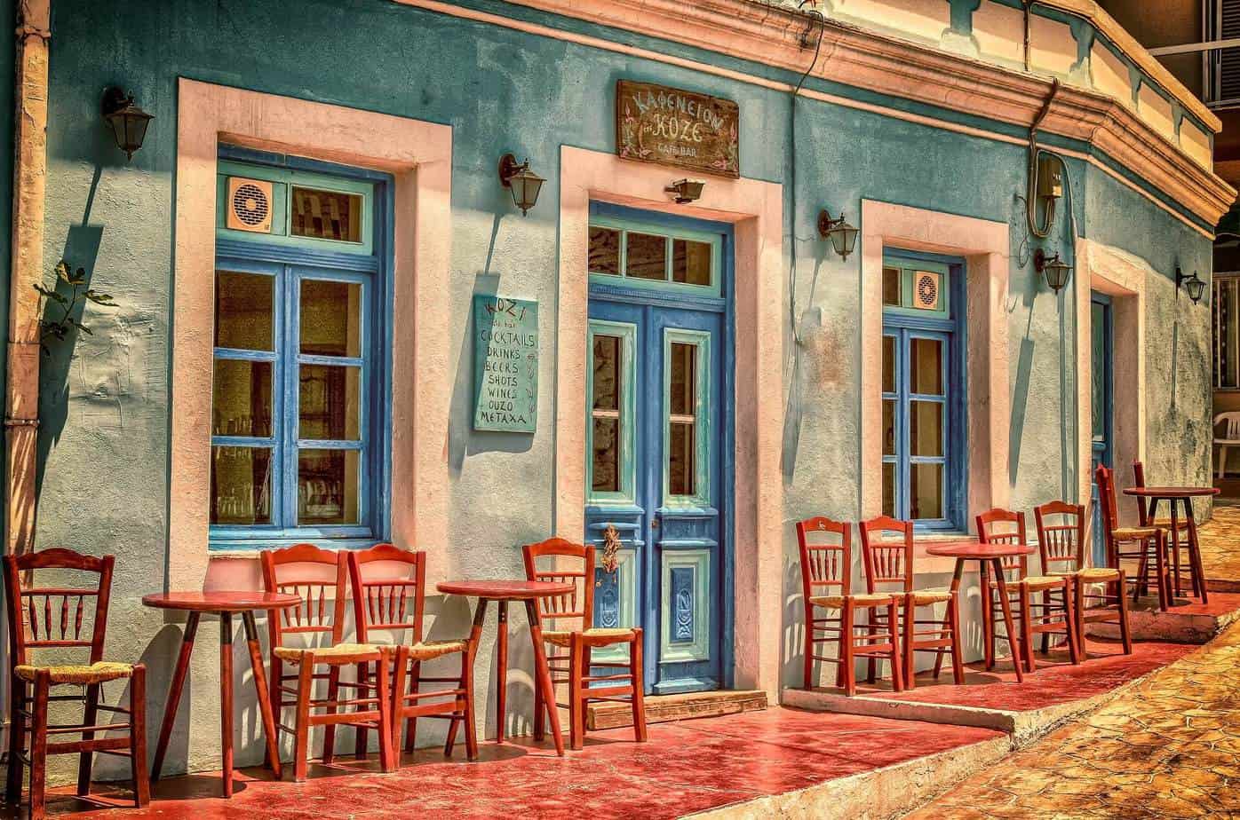 Turquoise cafe building with red chairs and table in front of it. Enneagram type five.