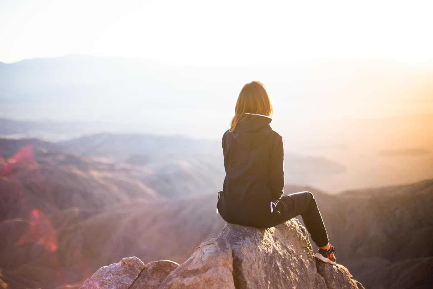 Woman sitting overlooking mountains.