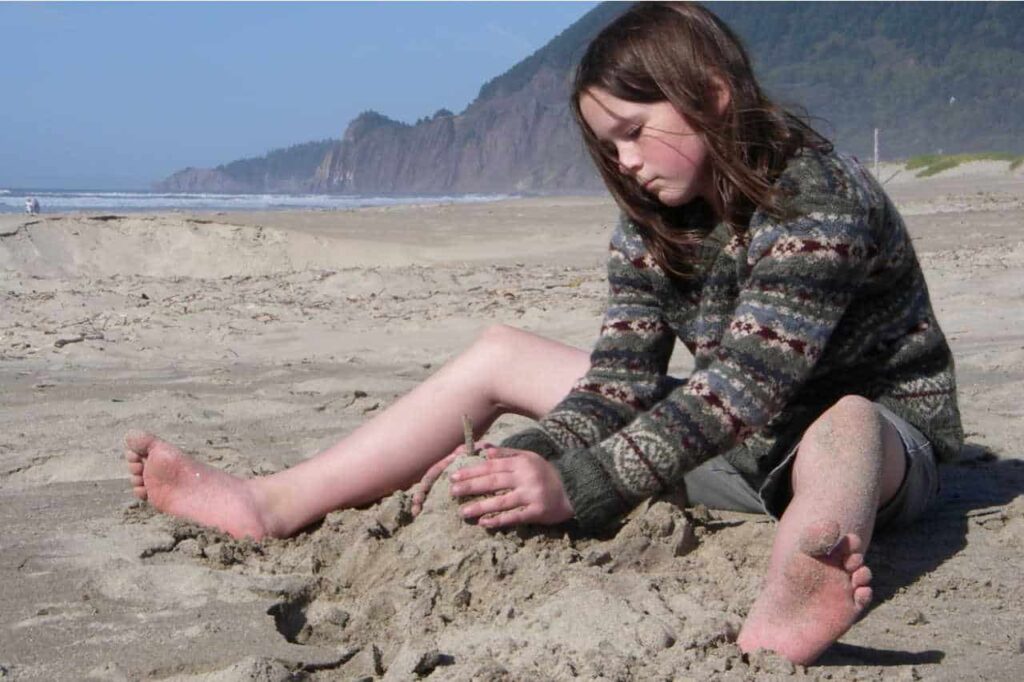 Girl playing in the sand on Manzanita Beach, Oregon
