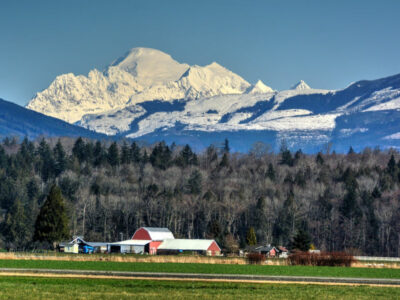 countryside in Skagit Valley, farmyard in the middle ground with a snowy mountain peak in back