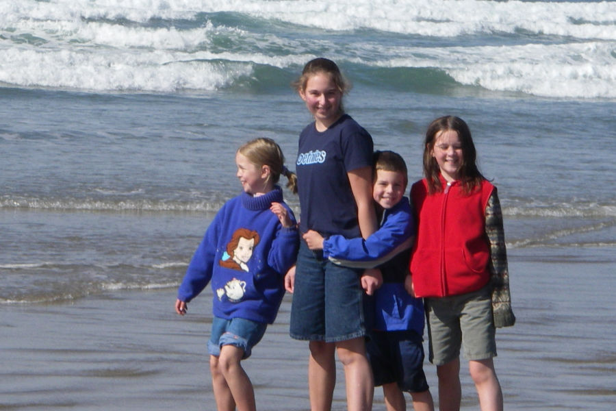 4 children hugging one another in front of the Pacific Ocean
