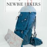 a teal blue daypack with hiking poles sticking out and a paper map folded and leaning against the front of the pack