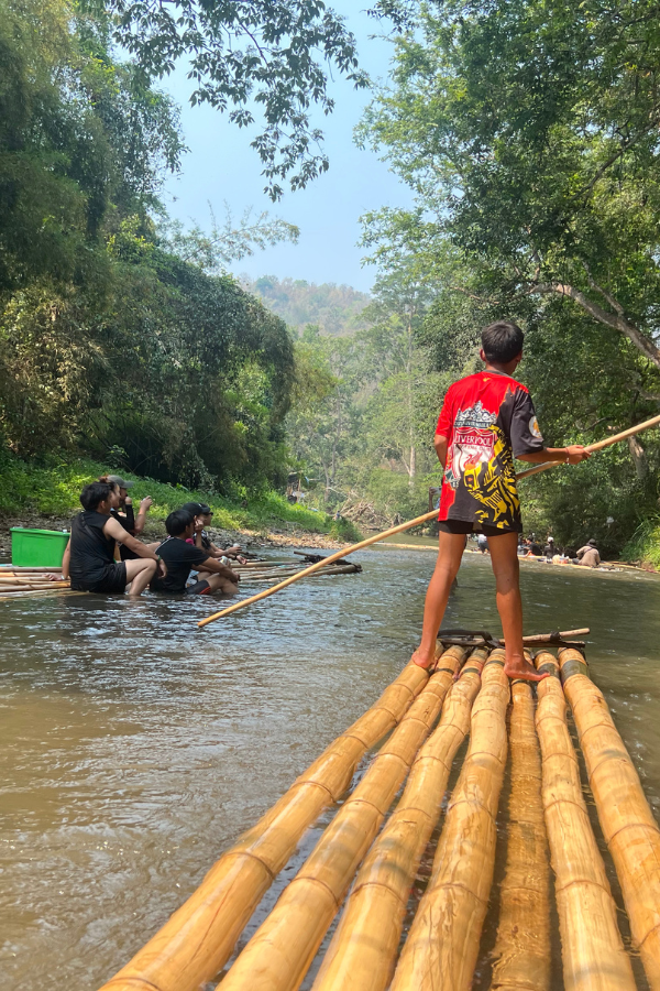 A bamboo raft, being steered by a Thai boy, going down the Tawan River
