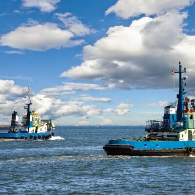two blue tugboats in the water