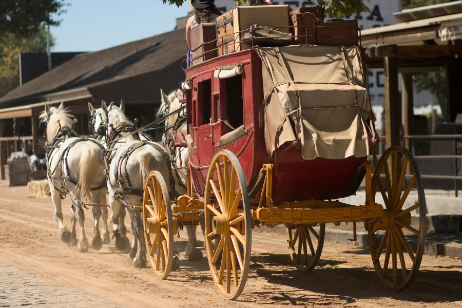 a red stagecoach being pulled by four white horses