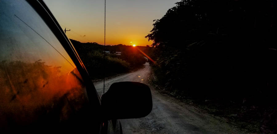 Sunset from car window while on a dirt road.